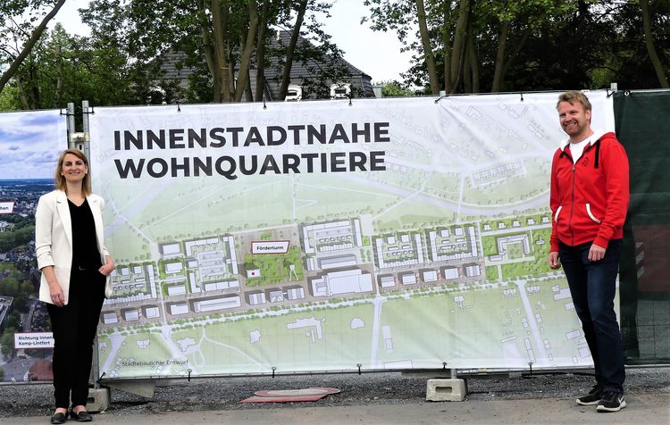 Andreas Iland und Sandra Nierfeld (v.l.) präsentieren die angebrachten Bauzaunbanner im Zechenpark. Foto: Lea Mispelkamp, Landesgartenschau Kamp-Lintfort 2020 GmbH