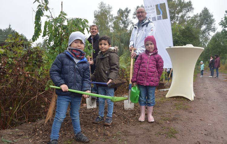 Unterstützt von den Kindern der Kita Ensdorf pflanzten Jörg Wilhelmy (1.v.l.), Bürgermeister der Gemeinde Ensdorf, und Martin Strauß (2.v.l.), Geschäftsführer LA Plus, vier Robinien an der B51. Foto: BeckerBredel, Laura Ockenfels.